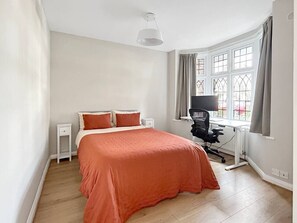A bedroom with a bed, a desk, and a chair.