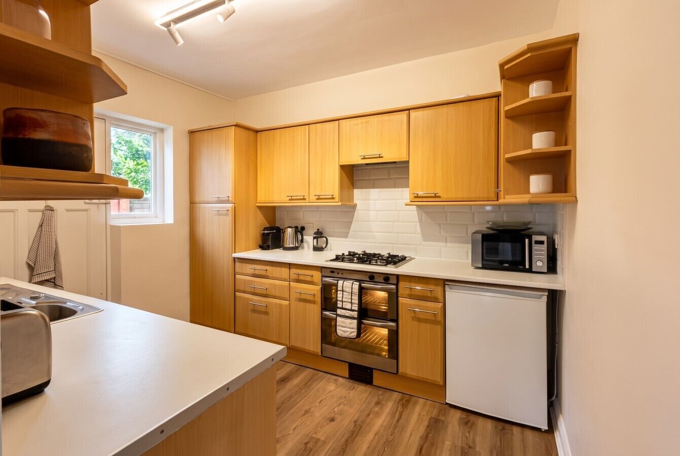 A modern kitchen with wooden cabinets, a stainless steel stove, a microwave, and a built-in oven.