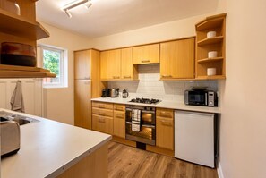 Une cuisine moderne avec des meubles en bois, une cuisinière en acier inoxydable, un four à micro-ondes et un four encastré.