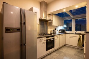 A modern kitchen with stainless steel appliances, a gas stove, and a built-in oven. - 3-Bed Flat · Sleeps 6 · Workspace · 10-Min Walk to Wimbledon Station (Greater London)