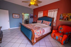 A bedroom with a bed, a chair, a ceiling fan, and a painting on the wall. - The Buck Island Overlook | Sleeps 12 (Christiansted)