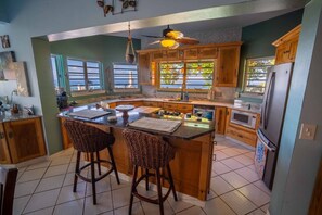 A kitchen with a central island, wooden cabinets, and a ceiling fan. - The Buck Island Overlook | Sleeps 12 (Christiansted)