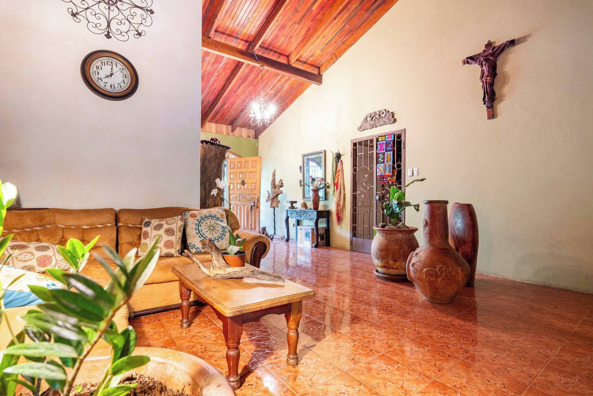 A spacious living area with a wooden ceiling, a sofa, a coffee table, and decorative vases.