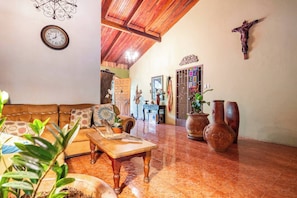 Uma sala de estar ampla com teto de madeira, um sofá, uma mesa de centro e vasos decorativos.