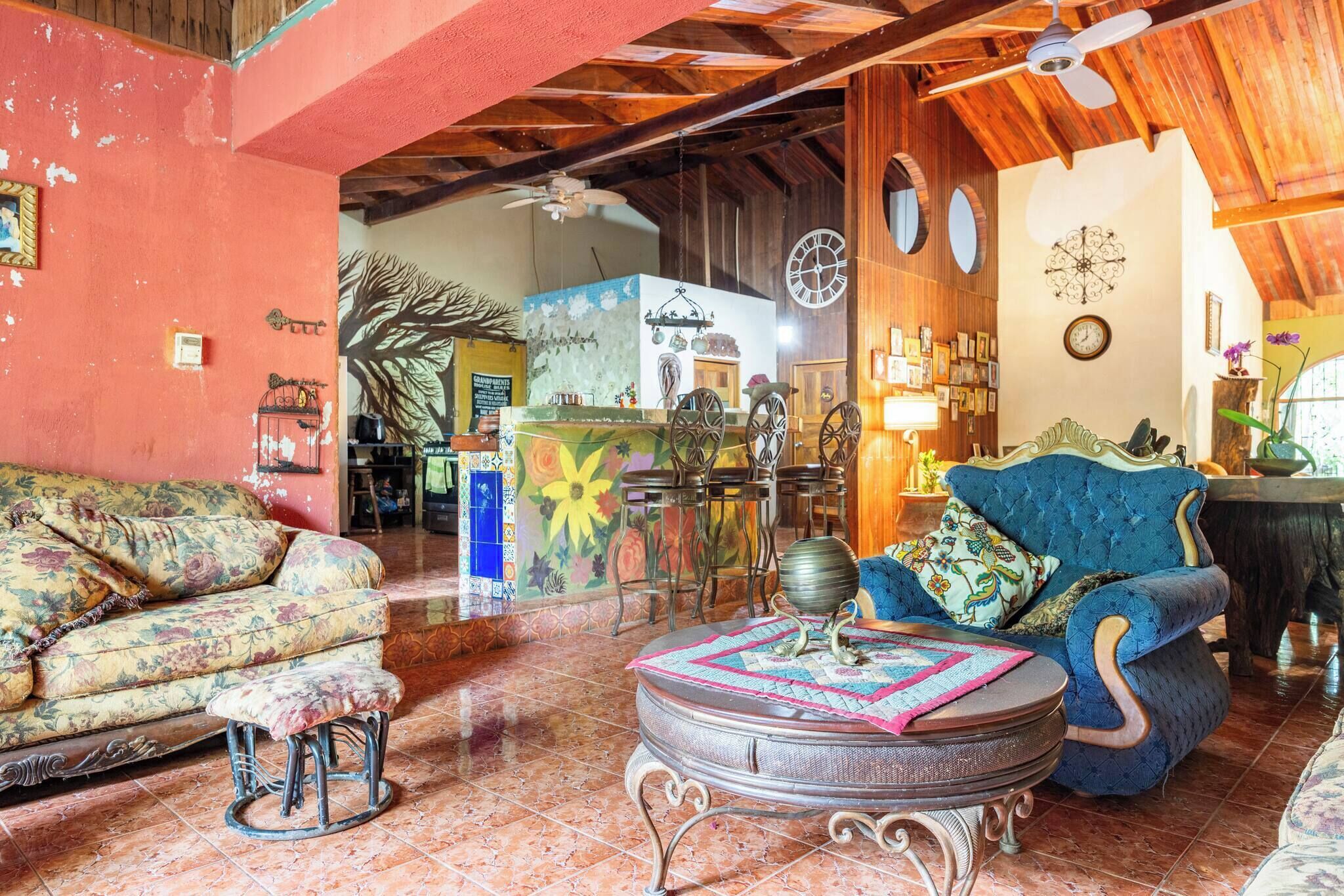 A cozy living room with a floral sofa, a blue armchair, and a round coffee table.