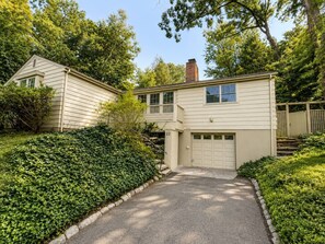 Ein zweistöckiges Haus mit Garage, umgeben von gepflegten Hecken und Bäumen.