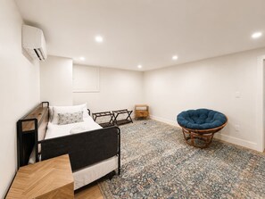 Ein Schlafzimmer mit einem Bett, einem Sessel, einem kleinen Tisch und einem gemusterten Teppich.