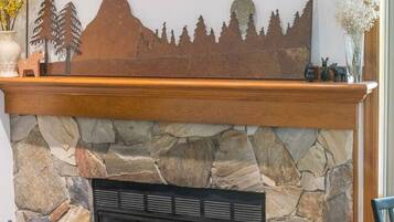 A stone fireplace with a mantel, a fire screen, and a fire extinguisher.