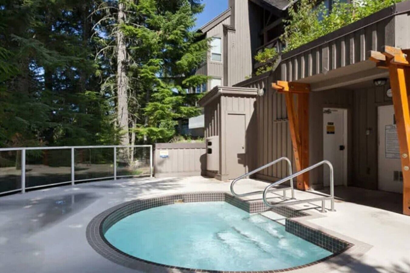 A circular hot tub with a metal ladder, surrounded by a wooden deck and a metal railing.