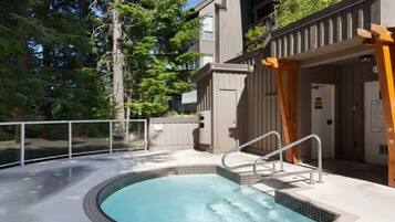 A circular hot tub with a metal ladder, surrounded by a wooden deck and a metal railing.