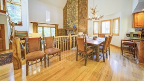 A spacious dining area with a high stone fireplace, wooden dining table, and chairs. - Adirondacks 6 | Fireplace, Restaurant, Pool, Spa (Blowing Rock)