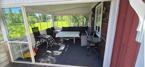 A covered patio area with a sofa, a table, and chairs.