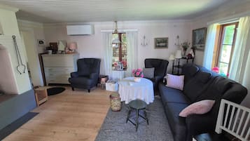 Ein gemütliches Wohnzimmer mit Kamin, einer Couch, einem Esstisch und einem Fenster mit Vorhängen.