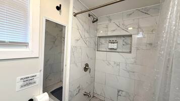 A bathroom with a shower, toilet paper, and a sign indicating flush-only use.