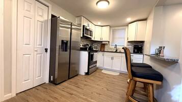 Una cocina moderna con armarios blancos, electrodomésticos de acero inoxidable y piso de madera.