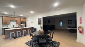 Una cocina moderna con armarios de madera, una isla central con taburetes y un comedor con una mesa redonda y sillas.