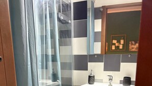 Un bagno con box doccia in vetro, un lavabo con dispenser di sapone in marmo e uno specchio sopra.