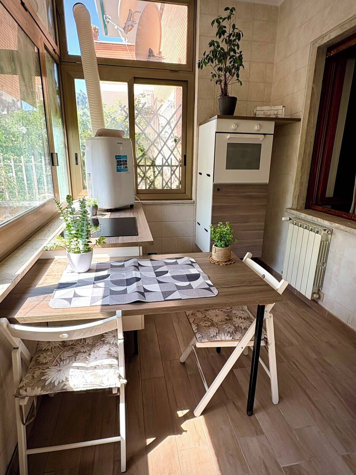 A compact kitchen with a dining area, a built-in oven, and a window with a view of the outside.