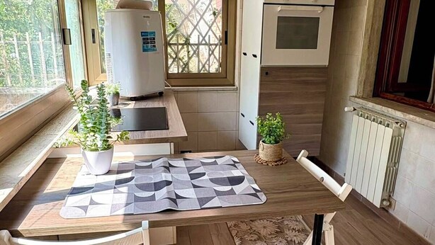 Una cucina compatta con angolo ristoro, forno integrato e finestra vista esterna.