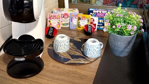 Un piano di lavoro in cucina con una macchina da caffè, una pianta in vaso e diversi prodotti confezionati.