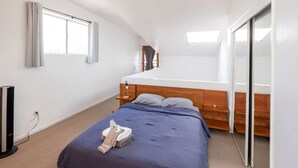 A bedroom with a bed, a bedside table, a mirror, and a window. - Bright 2 Bed Venice Loft (Los Angeles)
