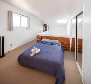 A bedroom with a bed, a bedside table, a mirror, and a window. - Bright 2 Bed Venice Loft (Los Angeles)