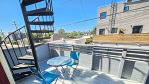 A covered outdoor patio with a table and chairs, a wooden fence, and a building in the background. - Bright 2 Bed Venice Loft (Los Angeles)