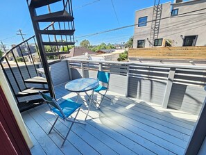 A covered outdoor patio with a table and chairs, a wooden fence, and a building in the background. - Bright 2 Bed Venice Loft (Los Angeles)