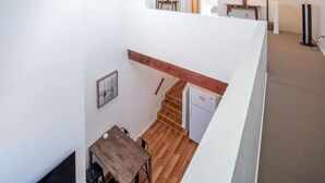 A modern interior with a wooden dining table, a staircase, and a kitchen area. - Bright 2 Bed Venice Loft (Los Angeles)