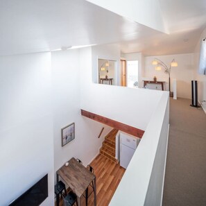 A modern interior with a wooden dining table, a staircase, and a kitchen area. - Bright 2 Bed Venice Loft (Los Angeles)