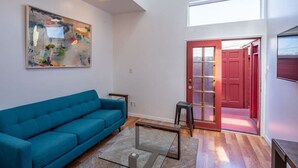 A modern living room with a blue sofa, a glass coffee table, and a painting on the wall. - Bright 2 Bed Venice Loft (Los Angeles)