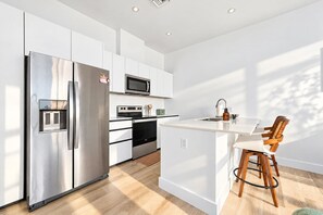 Een moderne keuken met roestvrijstalen apparatuur, een magnetron en een houten kookeiland met barstoelen.