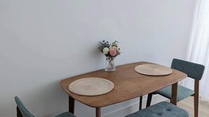 Ein Esstisch mit zwei Stühlen und einer Bank, eine Vase mit Blumen und eine helle Wand.