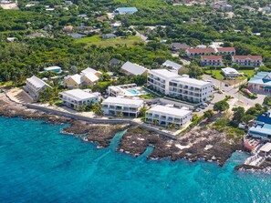 Luftaufnahme eines Küstenresorts mit mehreren Gebäuden, einem Schwimmbad und einer felsigen Küstenlinie.