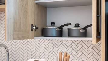A kitchen with wooden cabinets, a herringbone tile backsplash, a stainless steel sink, a roll of paper towels, a spice rack, and a toaster.
