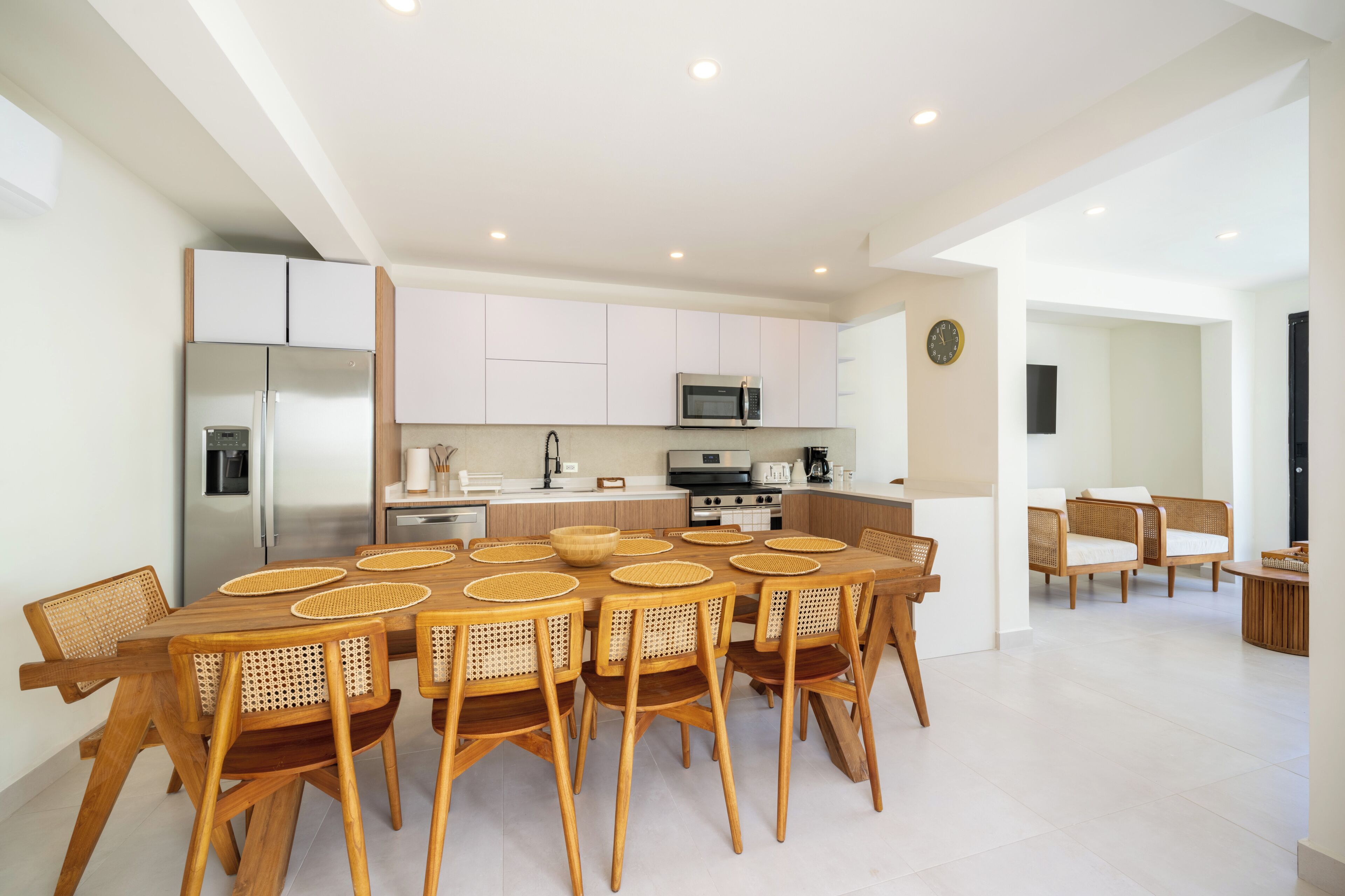 A modern kitchen with white cabinets, stainless steel appliances, and a dining area with a wooden table and chairs.