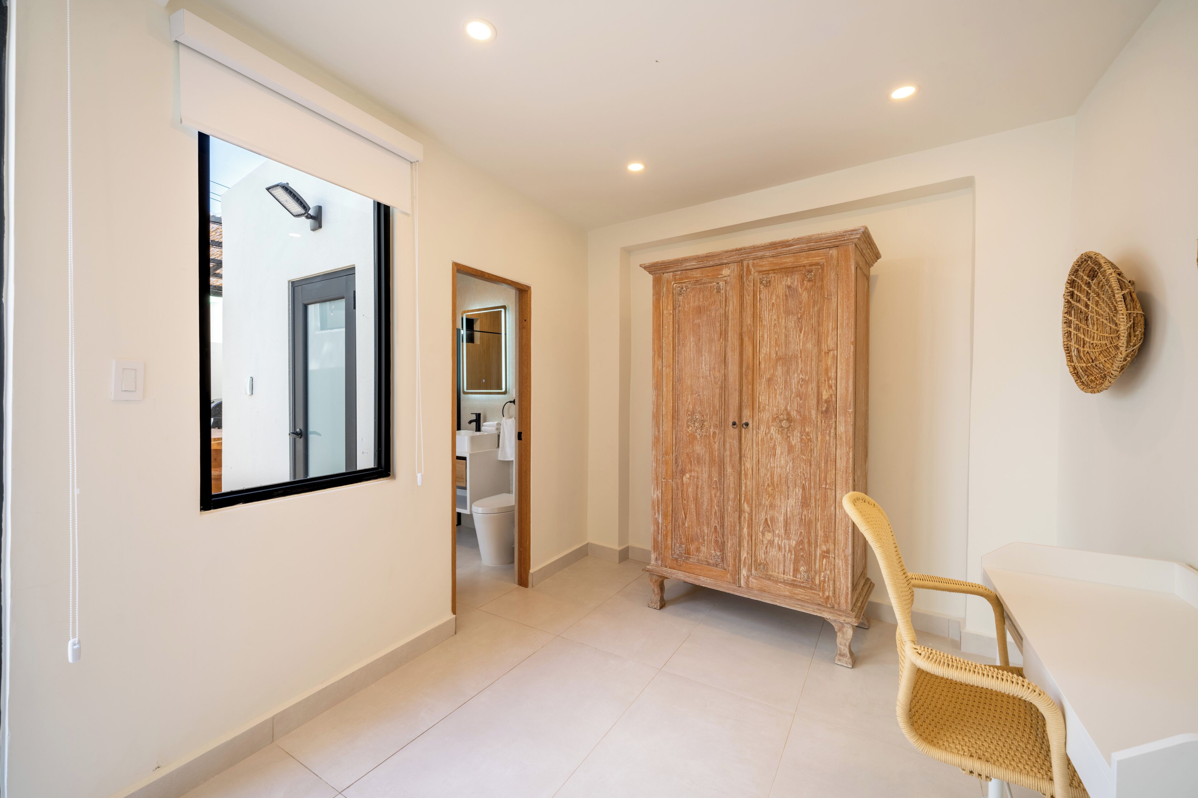 A hallway with a large mirror, a wardrobe, and a wicker chair.