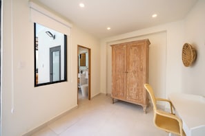 A hallway with a large mirror, a wardrobe, and a wicker chair. - 5BR Private Pool Retreat Walk to Ocean Park Beach (San Juan)