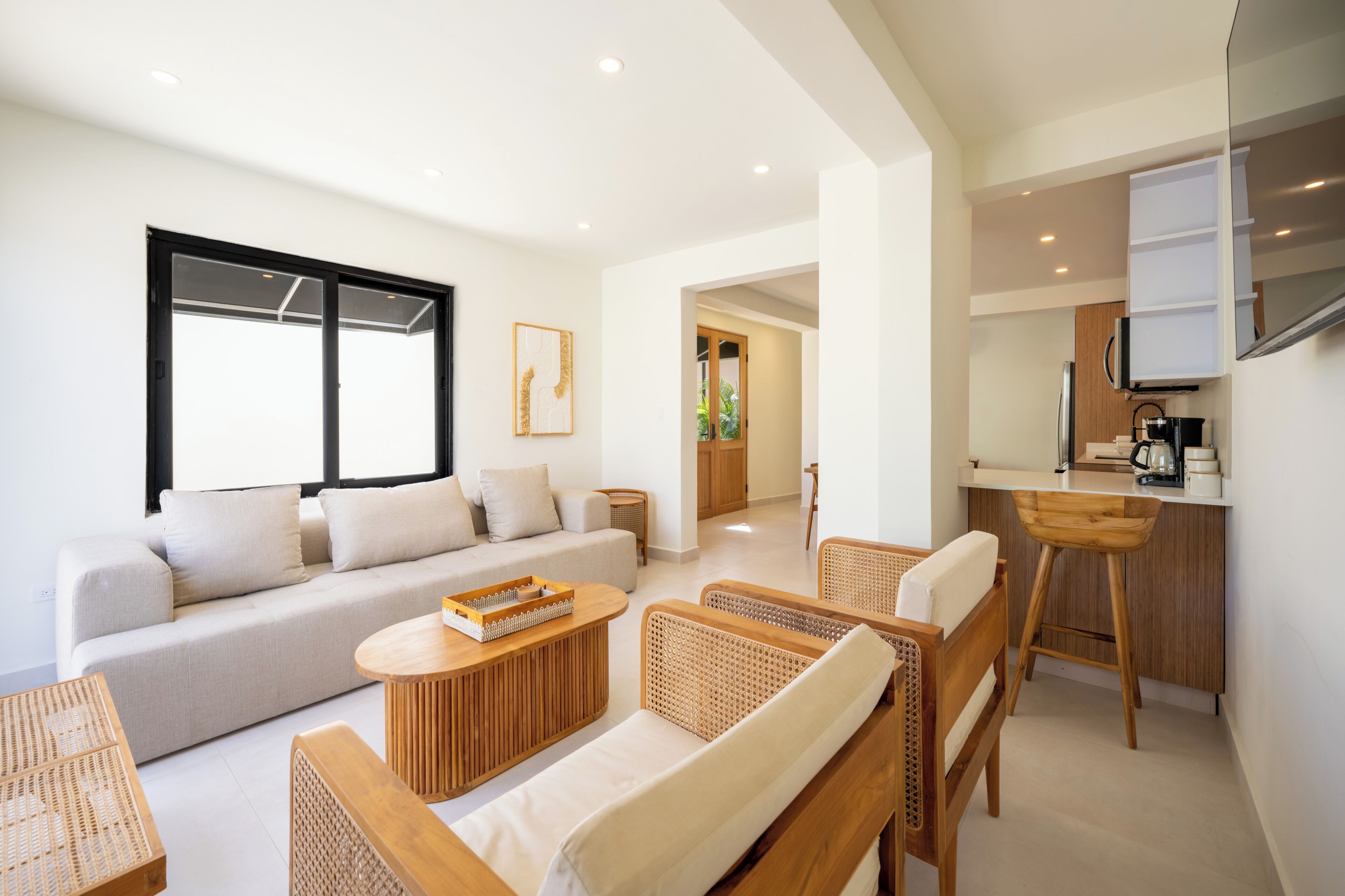 A modern living room with a sofa, a coffee table, and wicker chairs.
