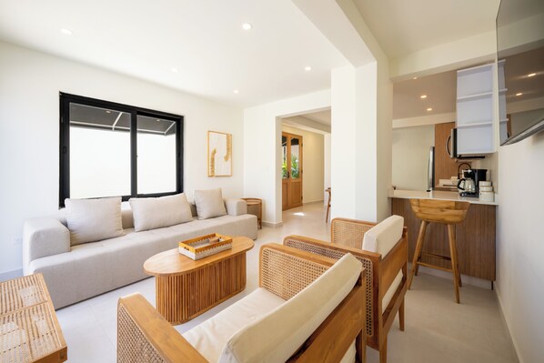 A modern living room with a sofa, a coffee table, and wicker chairs.