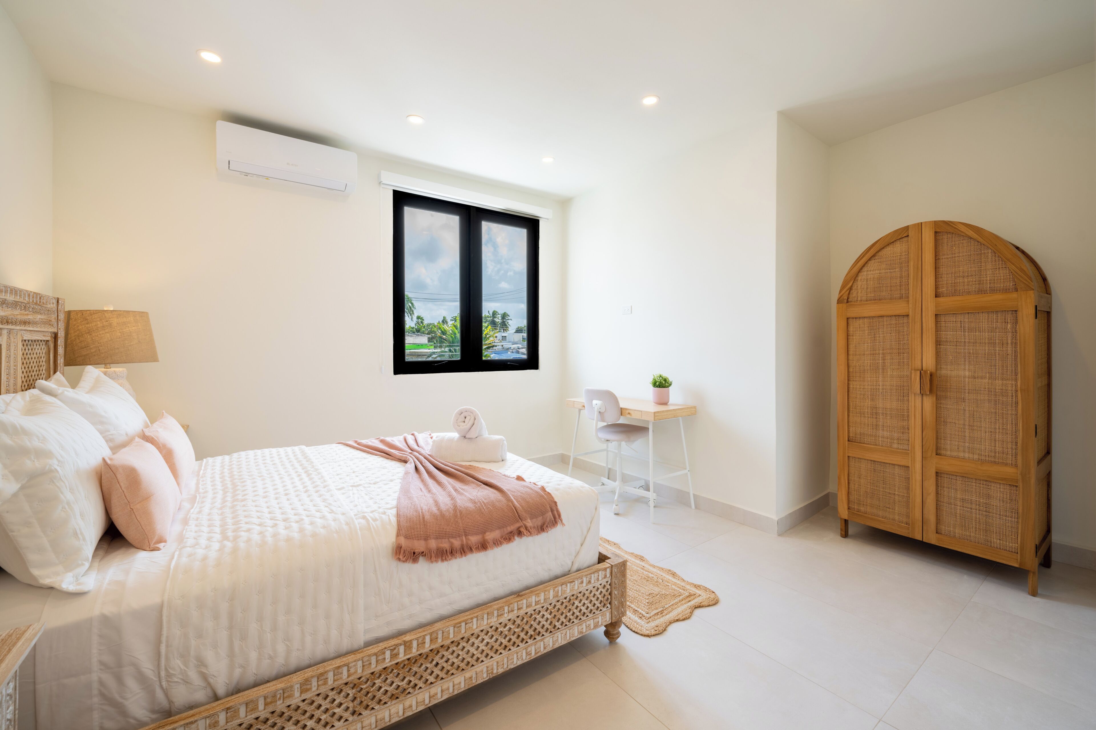 A bedroom with a bed, a desk, a chair, a wardrobe, and a window with a view.