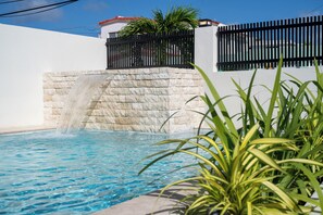 A swimming pool with a stone wall and a black fence. - 5BR Private Pool Retreat Walk to Ocean Park Beach (San Juan)