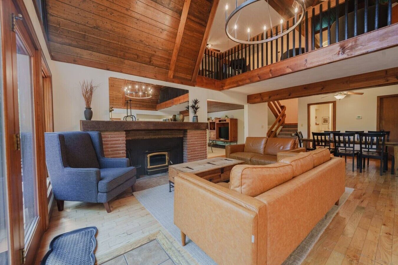 A spacious living area with a fireplace, leather sofas, and a dining area with wooden furniture.