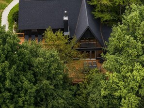 A modern house with a sloped roof, surrounded by dense greenery. - Crocketts: Pond Views, Seasonal Waterfall, Hot Tub (Logan)