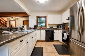 A modern kitchen with white cabinets, stainless steel appliances, and a window providing natural light. - Crocketts: Pond Views, Seasonal Waterfall, Hot Tub (Logan)
