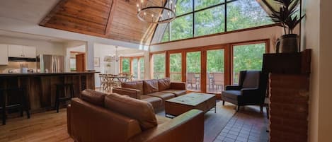 A spacious living area with a high ceiling, a dining table, and a kitchen area.