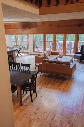 A spacious living area with a wooden floor, a sofa set, and a dining table with chairs. - Crocketts: Pond Views, Seasonal Waterfall, Hot Tub (Logan)