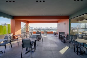 Terraza en la azotea con mobiliario exterior y vista a la ciudad.