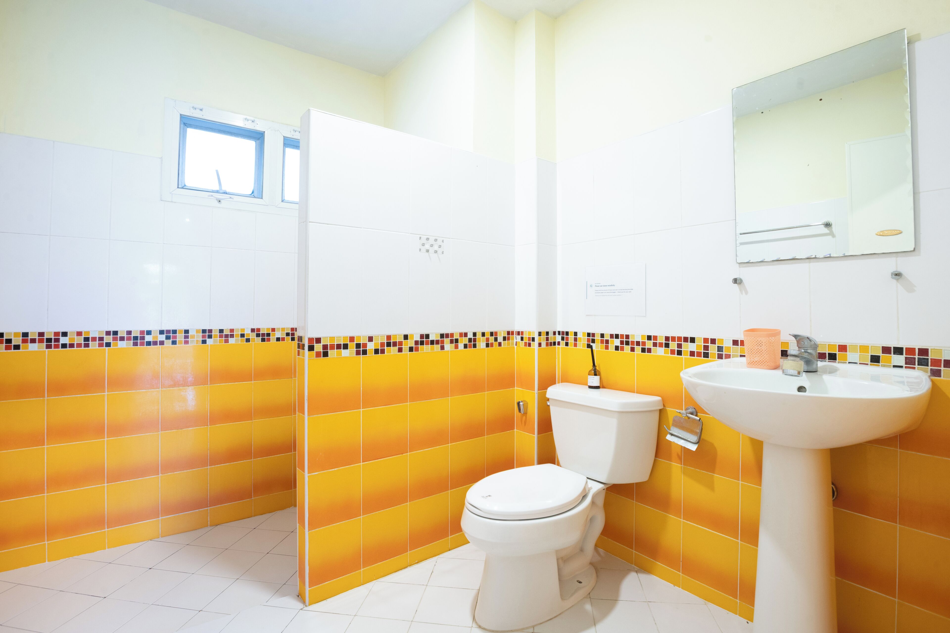A bathroom with a toilet, sink, and mirror.