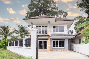 A two-story house with a balcony, large windows, and a gated entrance. - 4BR Family Home • Garden & Sala • Sleeps 9 • Near Airport (Nong Phueng)